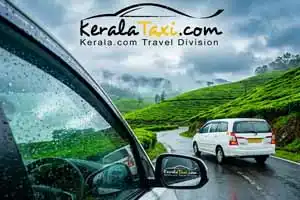 A passenger's point-of-view from inside a KeralaTaxi tourist vehicle looking at raindrops on the window, with another white taxi driving ahead on a winding road through the misty green tea plantations of Munnar, Kerala during the monsoon season.